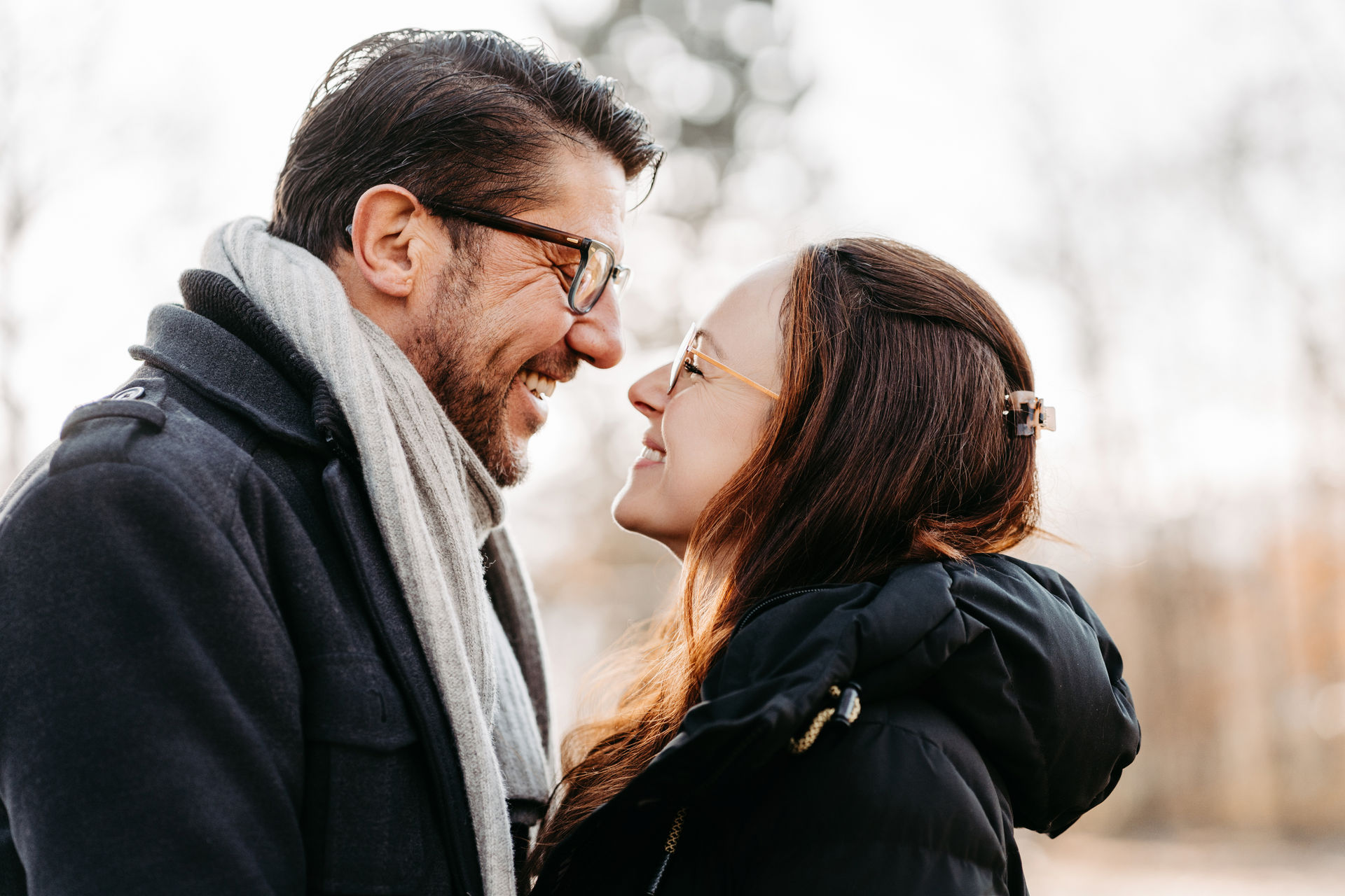 Eltern stehen Arm in Arm auf einer Wiese und blicken sich an.