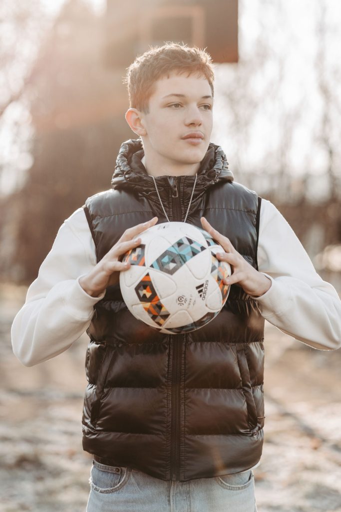 Kinder spielen Fußball auf einer Wiese während eines Familienfotoshootings