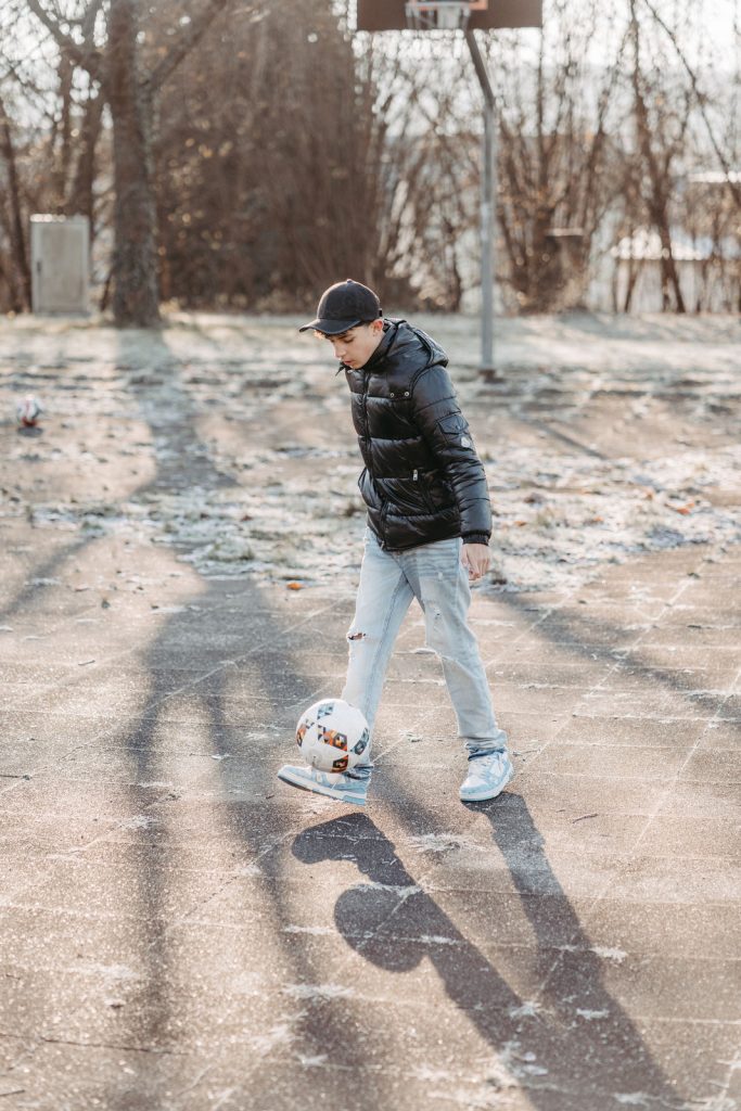 Kinder spielen Fußball auf einer Wiese während eines Familienfotoshootings