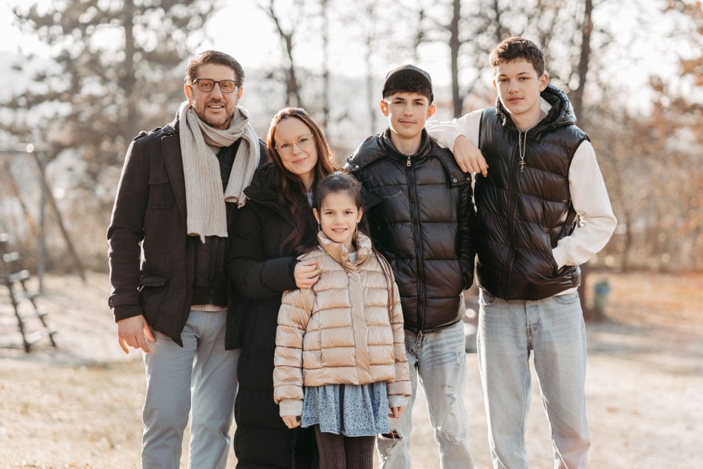 Familie läuft über eine Wiese und lacht miteinander während eines Fotoshootings.