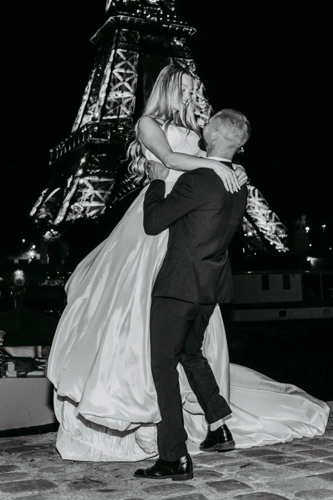 Braut und Bräutigam lachen vor dem Eiffelturm in Paris während eines Hochzeitsfotoshootings.