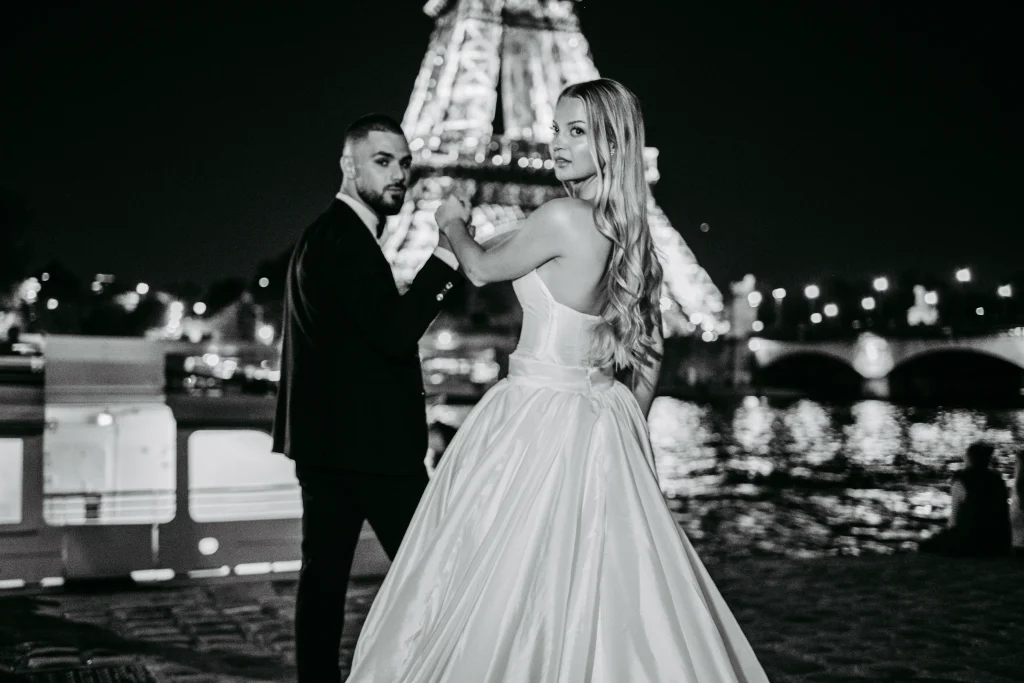 Brautpaar steht vor dem beleuchteten Eiffelturm in Paris bei Sonnenuntergang.
